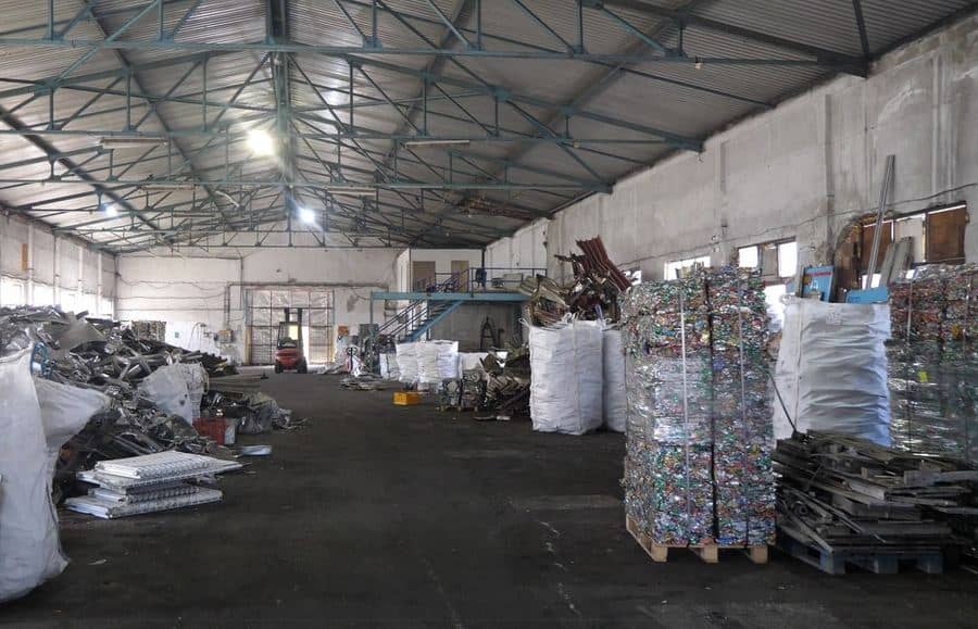 The hall with heaps of scrap metal, bulk bags and pallets of baled cans