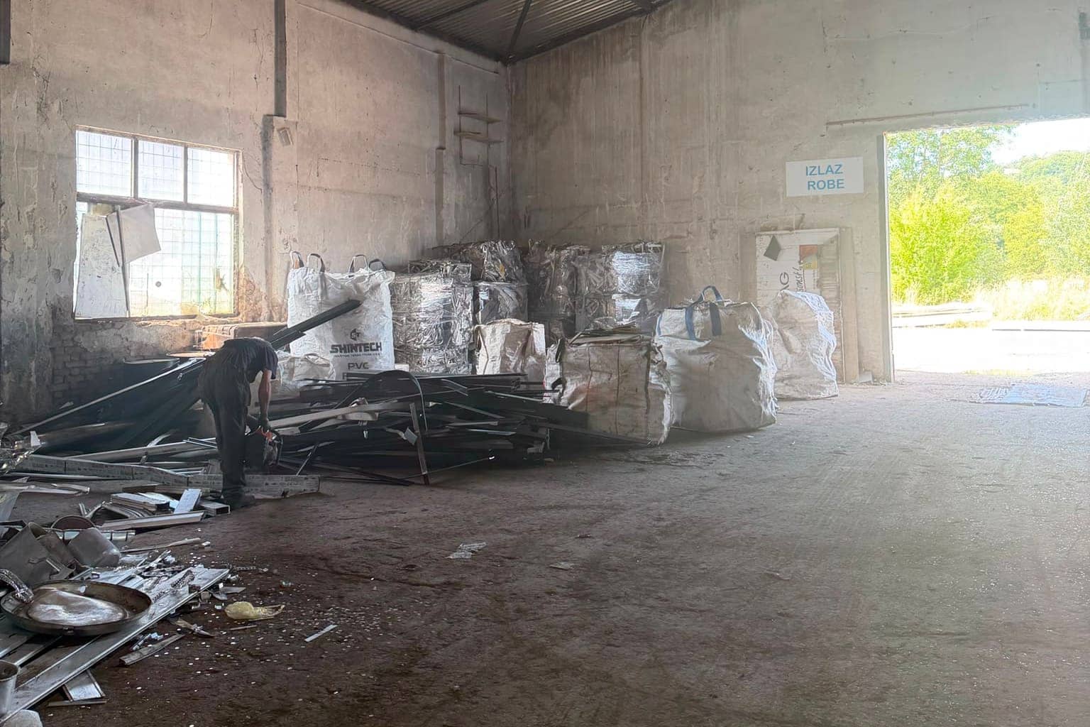 Radnik rastavlja aluminijske i PVC prozorske profile uz složene bale i velike vreće